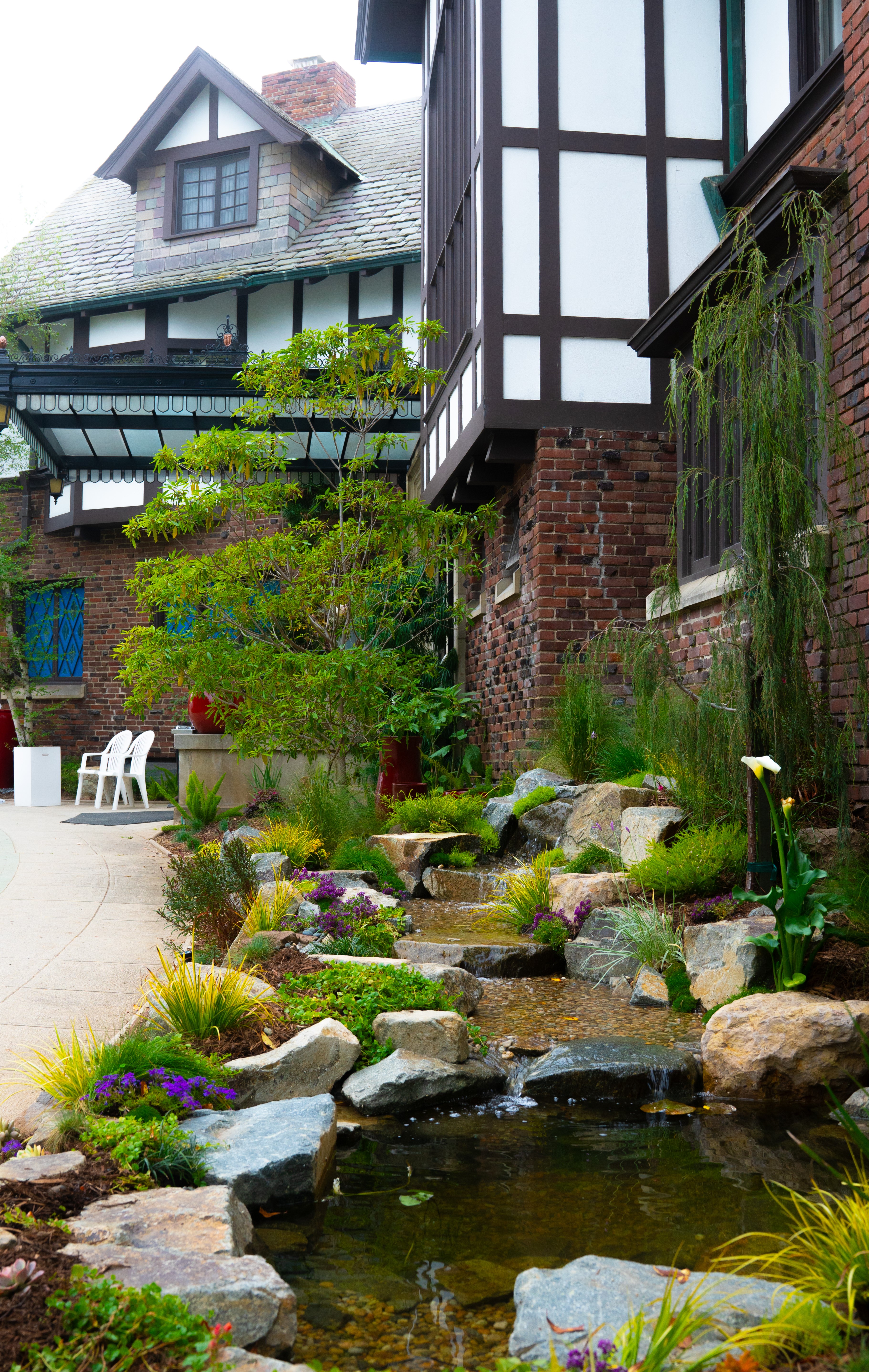 Pasadena garden with water feature beside a Tudor-style home