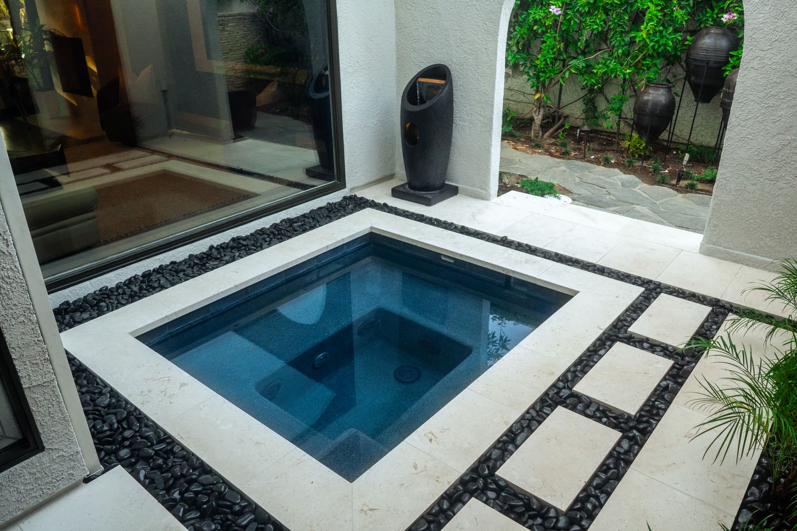The spa in its pale stone surround, ringed with polished black river rock