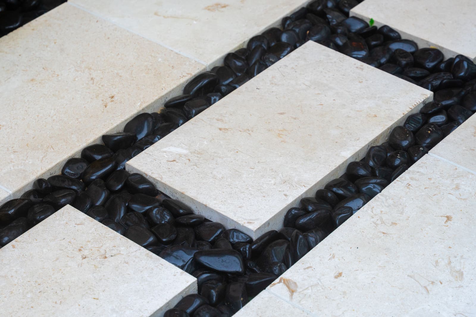 Detail of a pale stone stepper set in polished black river rock