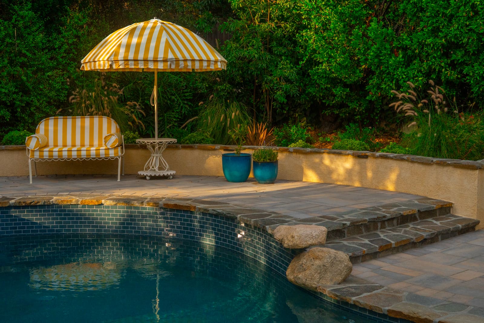 Pool and raised spa with flagstone coping, granite boulders and potted colour at the step