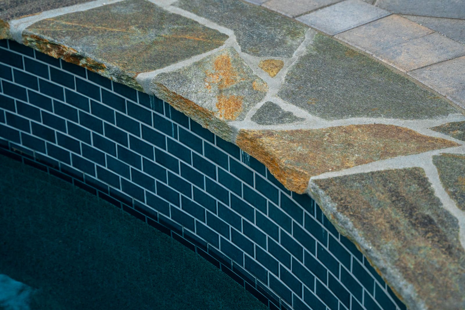 Detail of flagstone coping over the blue-tiled pool wall