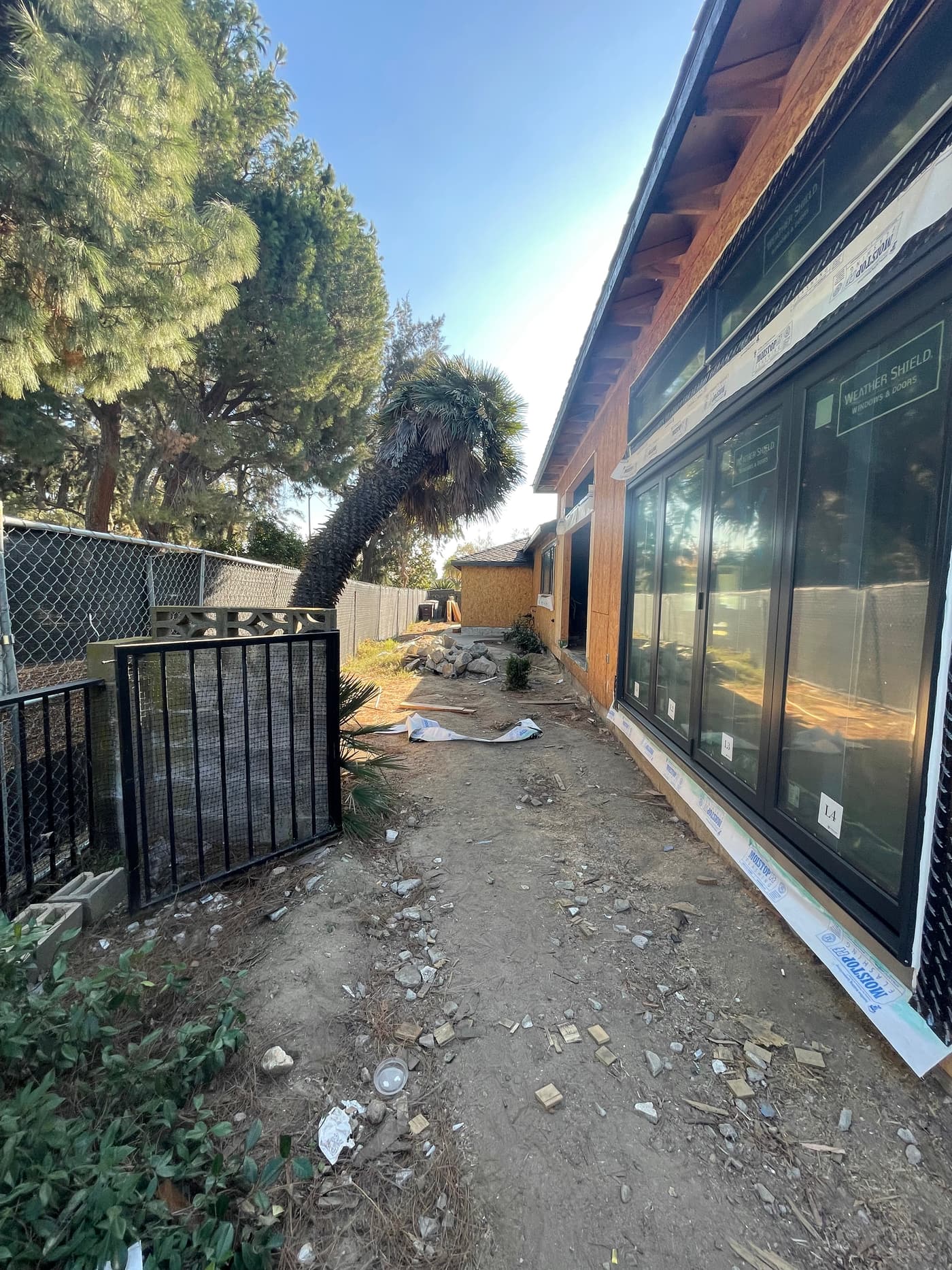 The side of the house during construction, a narrow dirt strip beside newly installed sliding doors