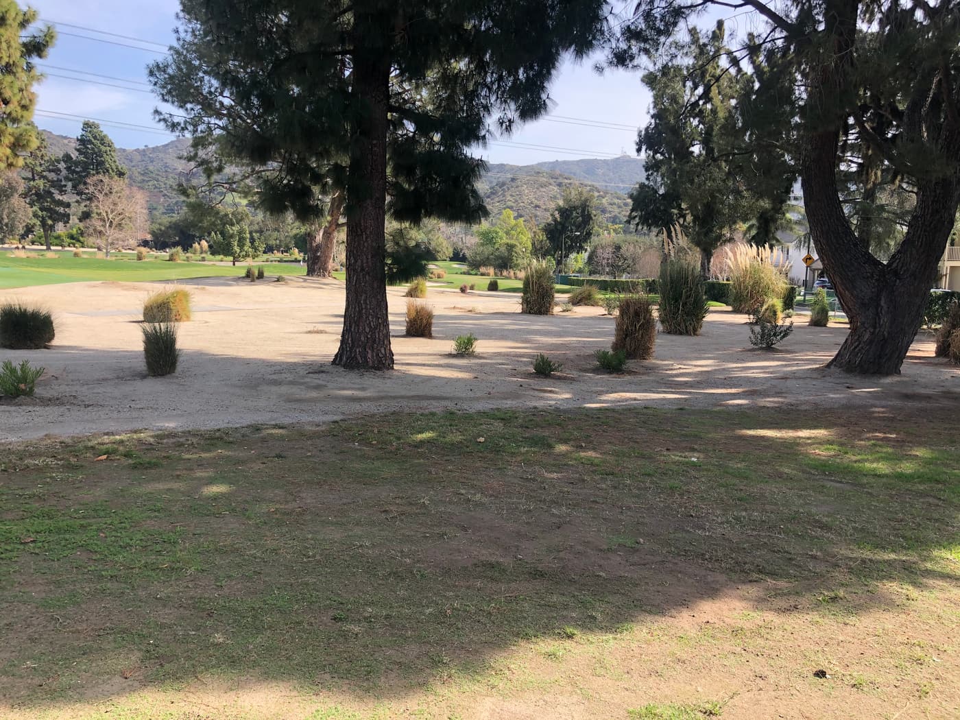 The back yard before construction: bare dirt and worn grass running out to the golf course fairway