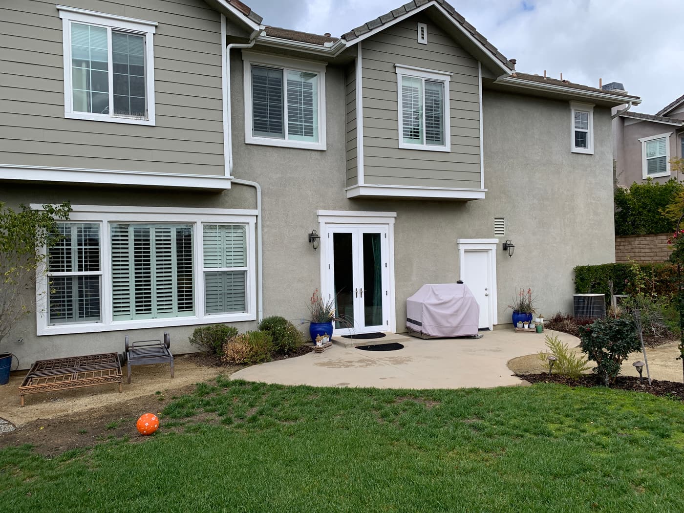 The rear elevation before construction, with a small concrete pad and a covered barbecue