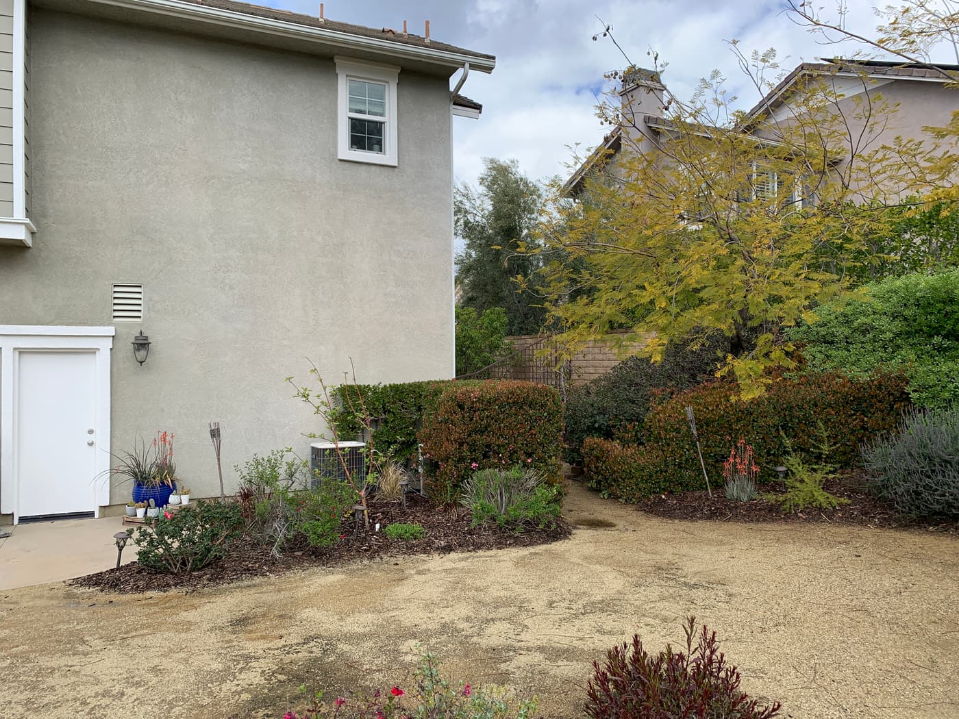 Bare dirt and worn lawn along the side of the house before construction