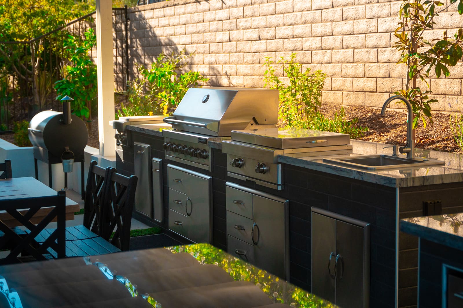 Outdoor kitchen run with a built-in grill, side burners and stainless drawers set into dark cabinetry