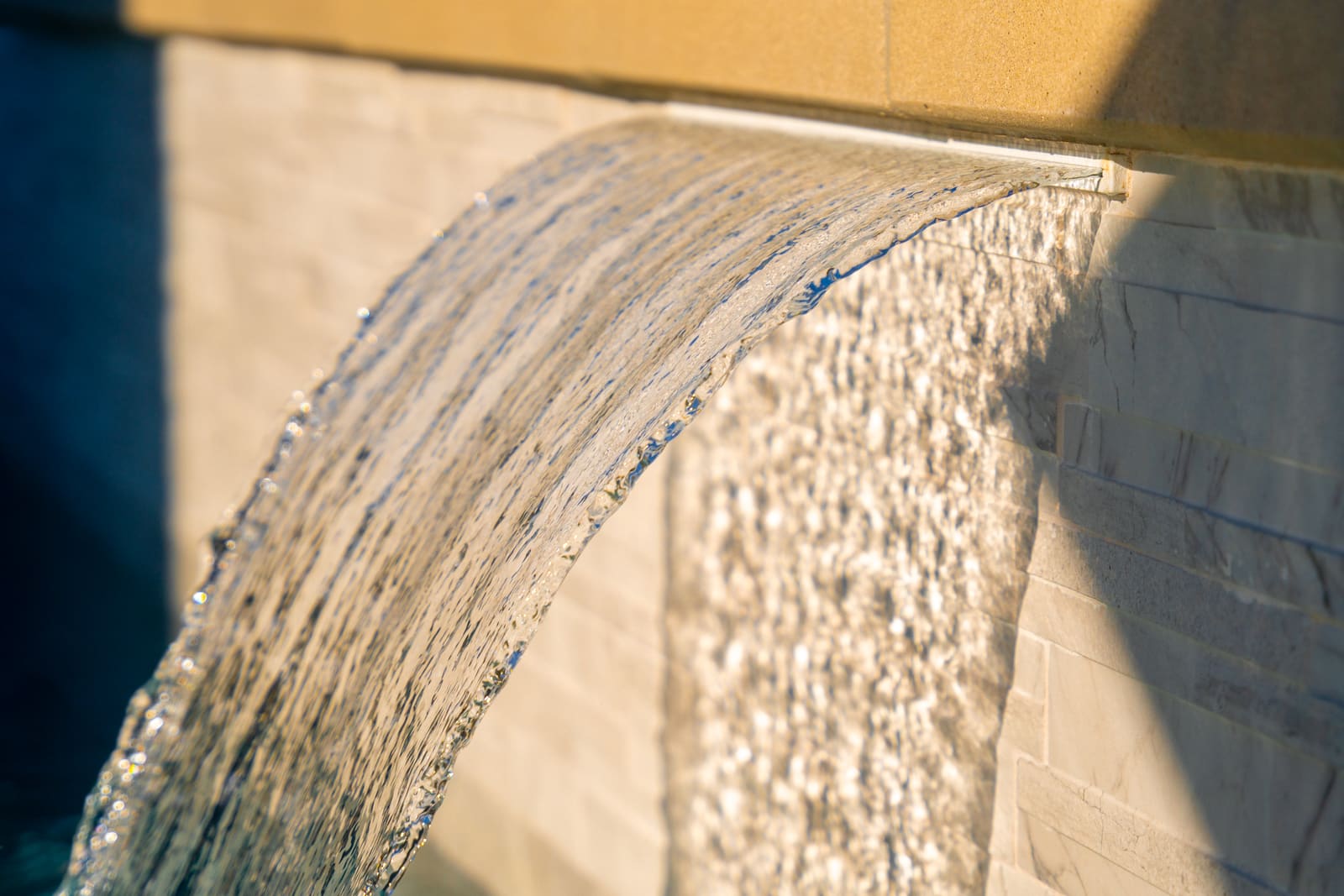 Water sheeting from a scupper down the tiled wall of the raised spa