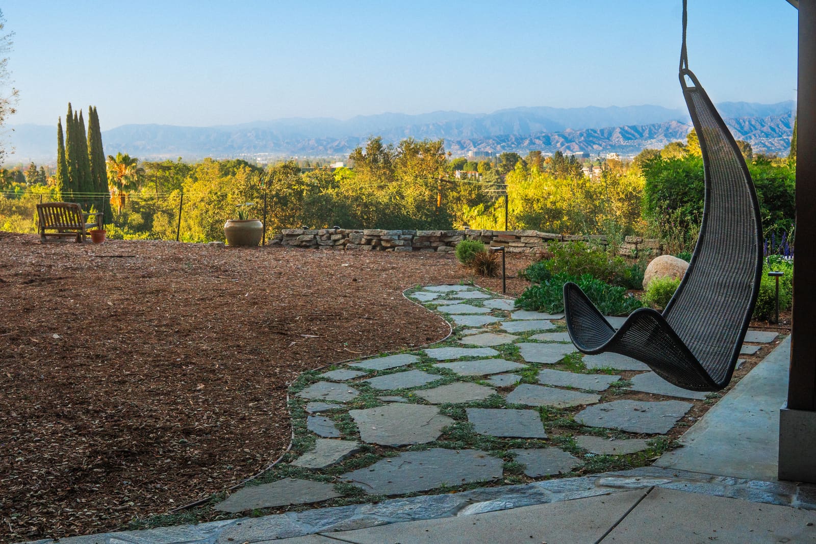 Bluestone flagstone path with planted joints curving across the decomposed granite terrace, the valley and mountains beyond