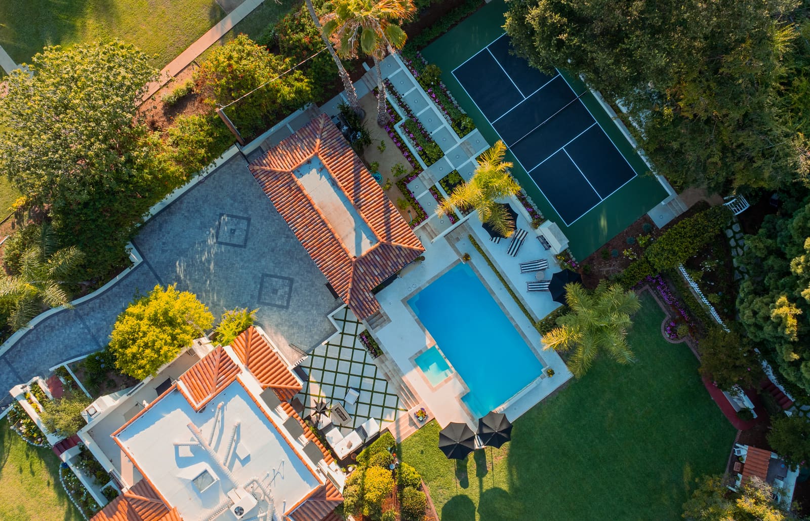 Aerial view of the Spanish Colonial estate, showing the rectangular pool, stone terraces, lawns and mature trees that surround the house