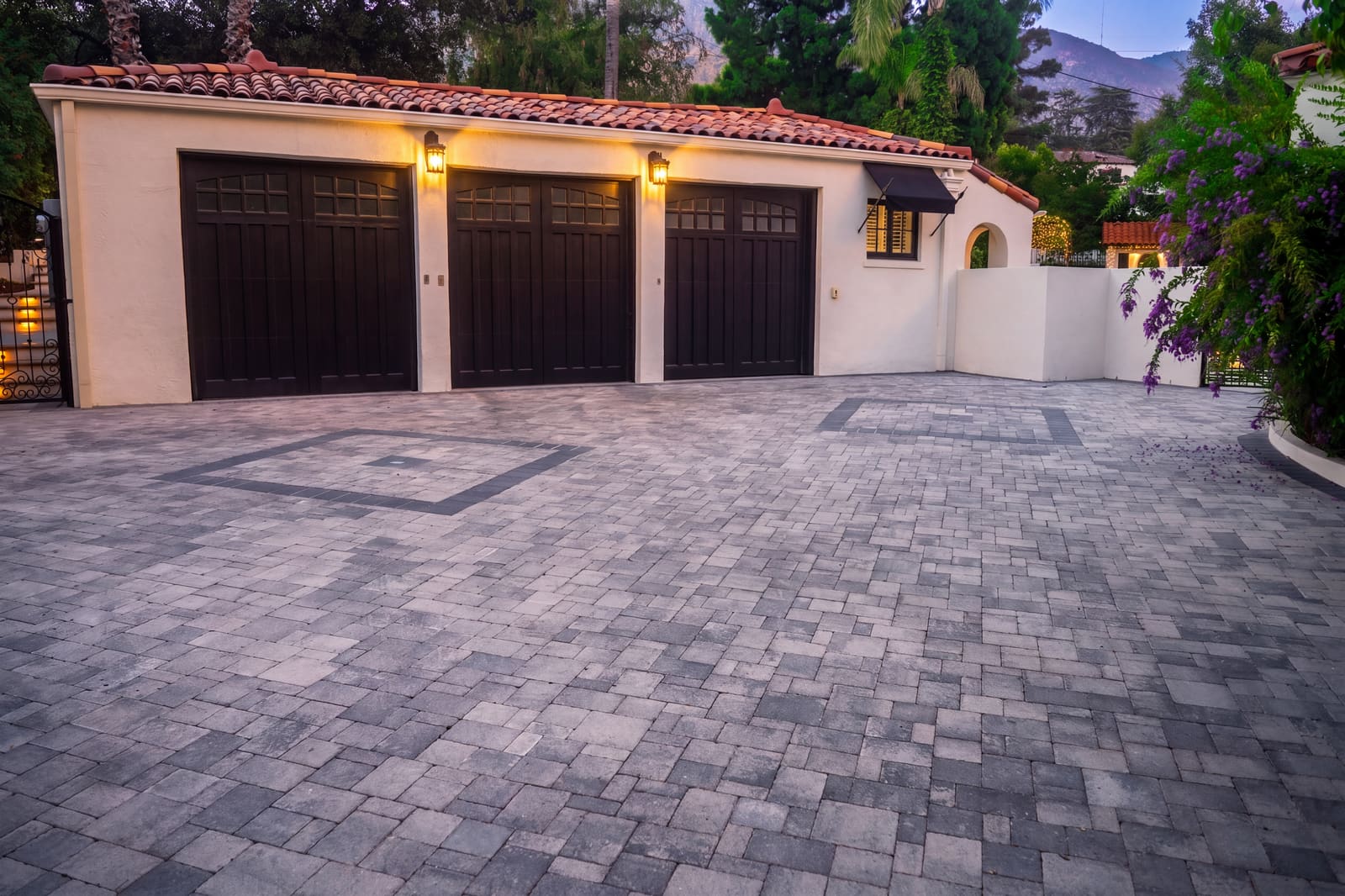 New paver driveway in front of the three-car garage with its dark timber doors