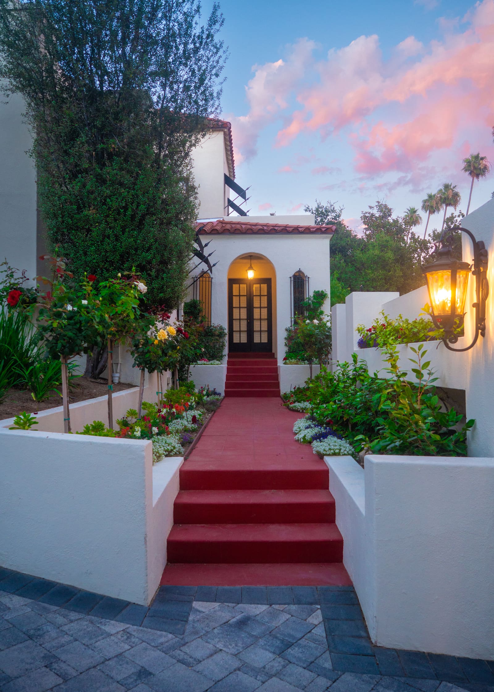 Front entry steps framed by white stucco planters filled with roses and boxwood