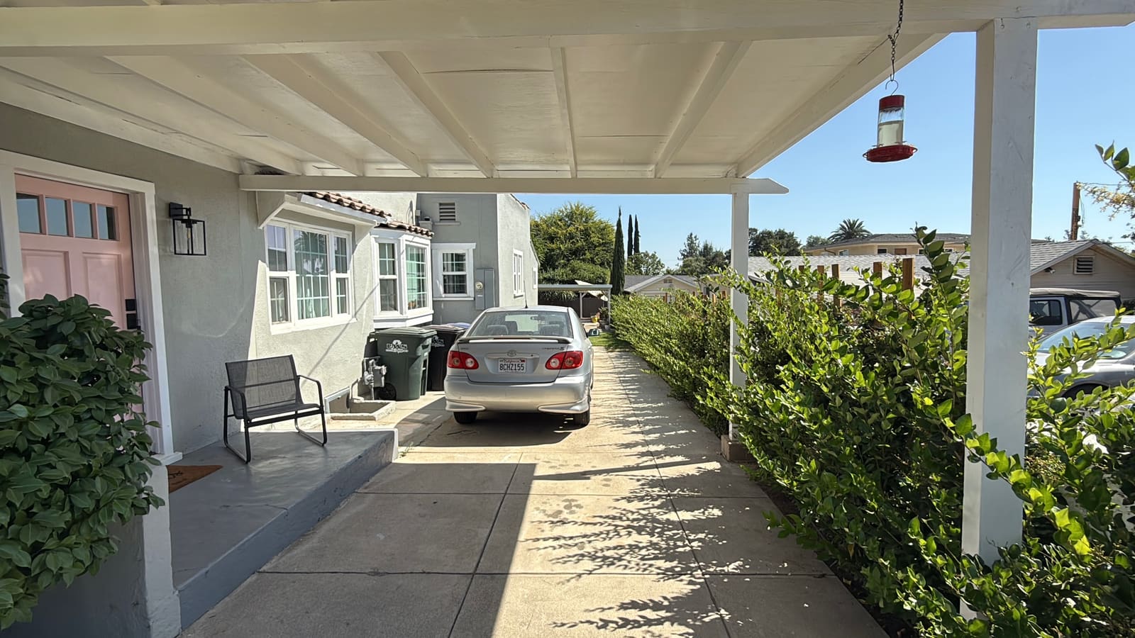 The side driveway and carport before construction, with the hedge already established along the fence line