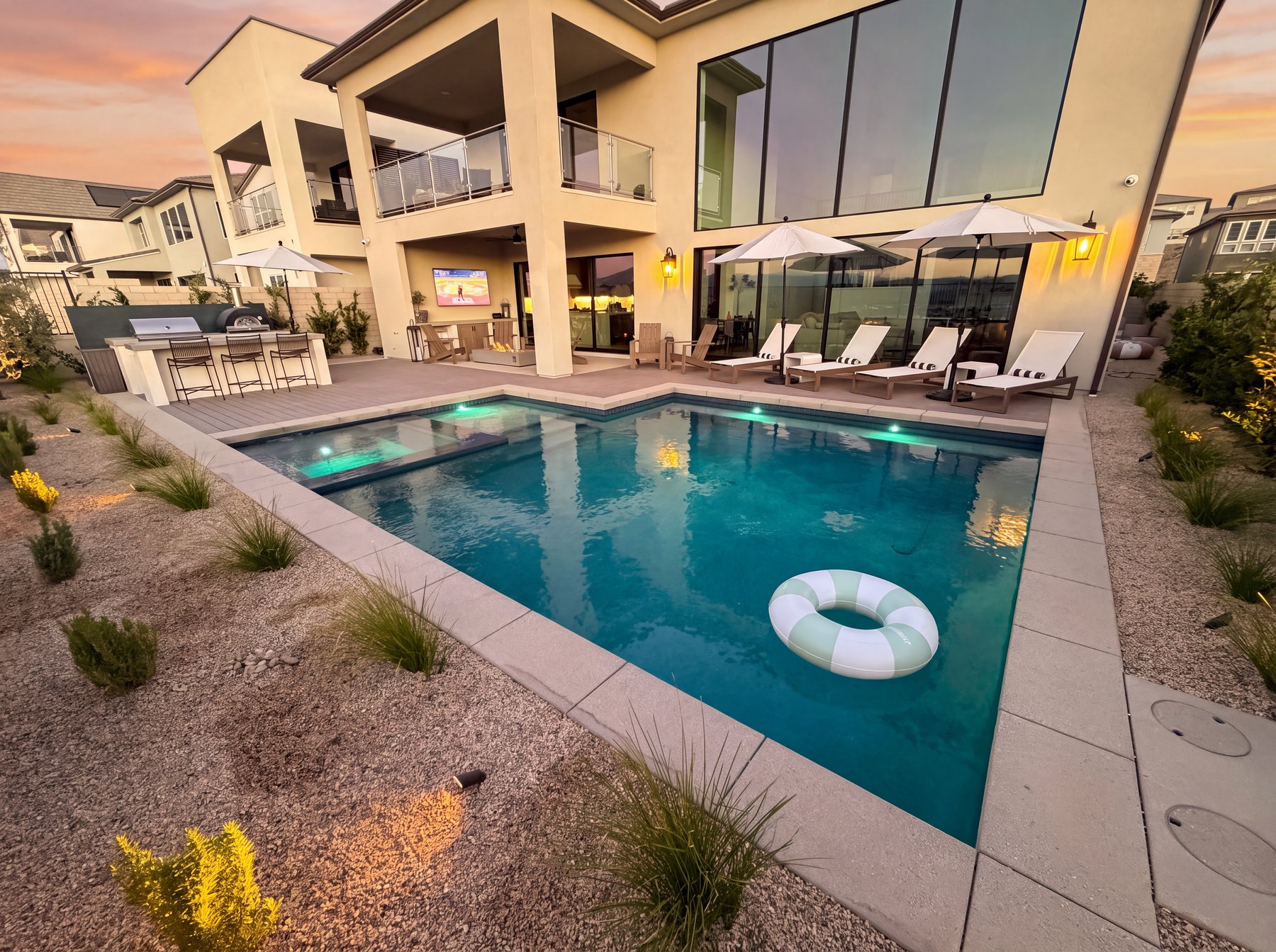 Modern courtyard pool with lounge chairs, low-water planting, and a contemporary home facade