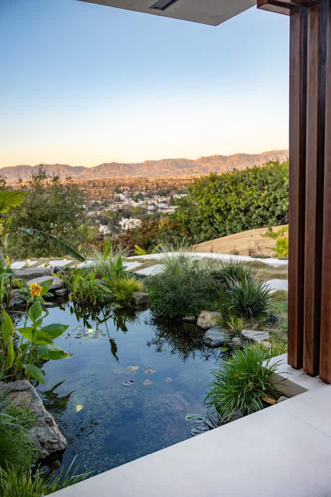 A koi pond on a hillside terrace overlooking a distant valley and mountain view