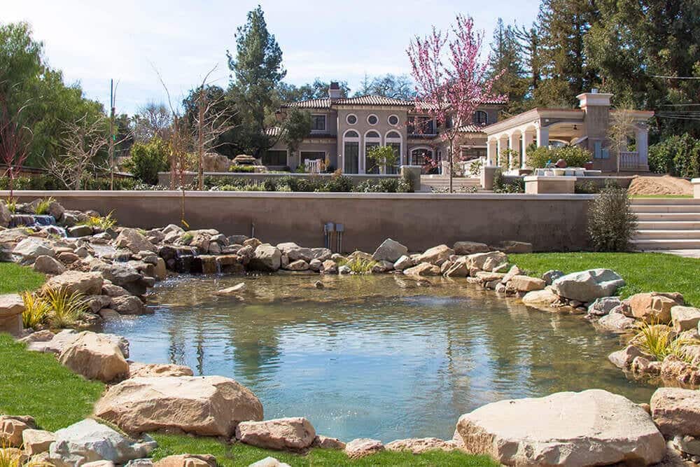 A large estate-scale pond with waterfalls set into a landscaped hillside