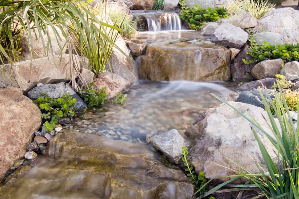 A finished pond and stream feature bordered by mature garden planting