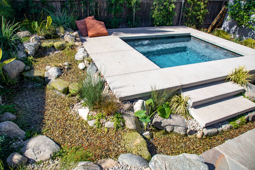 A pondless waterfall feeding into a spa area, framed by tropical planting