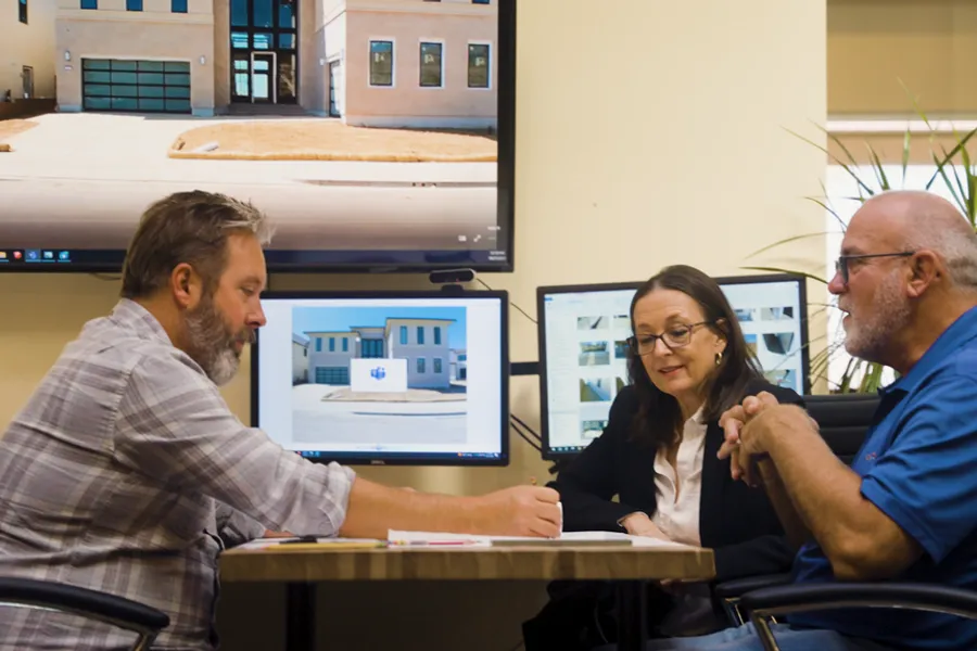 Pacific Outdoor Living designers reviewing a property plan with homeowners on screen in the studio
