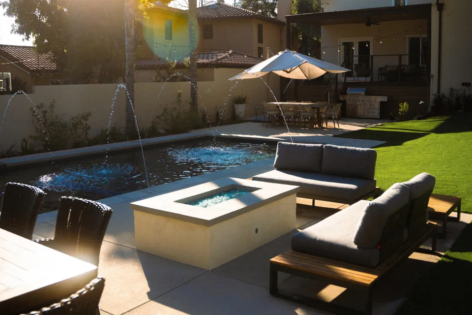 Small pool overlooking a larger pool with patio and patio furniture.