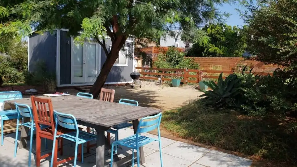 Fenced in backyard with table, plants, and studio in Los Angeles