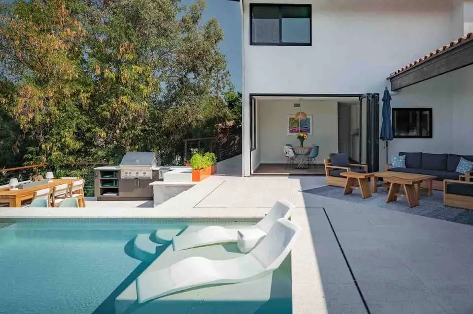 Rectangular pool behind a patio table, chairs, and umbrella.