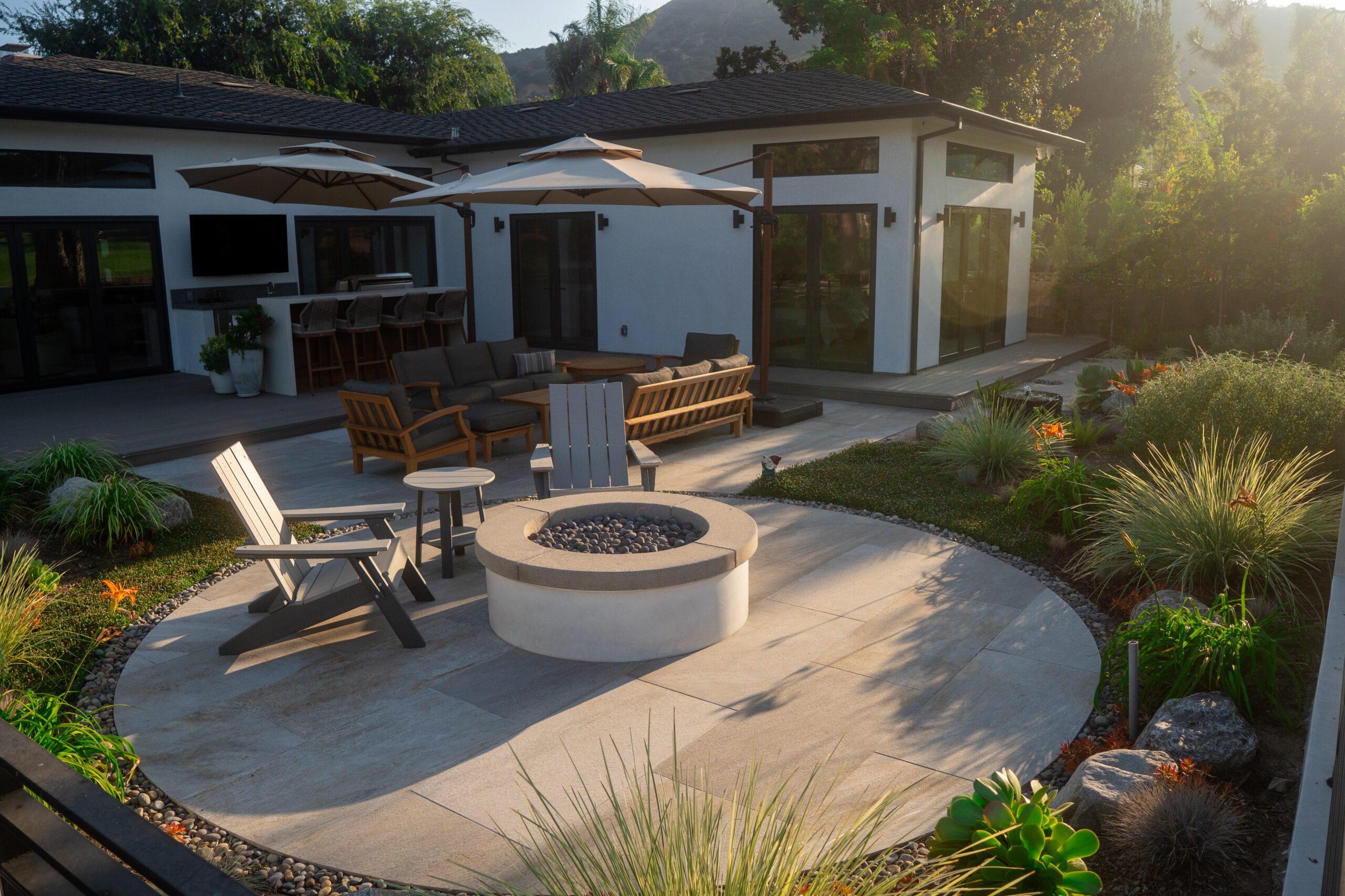 Completed backyard transformation with outdoor kitchen, patio, seating area, and firepit built by Pacific Outdoor Living