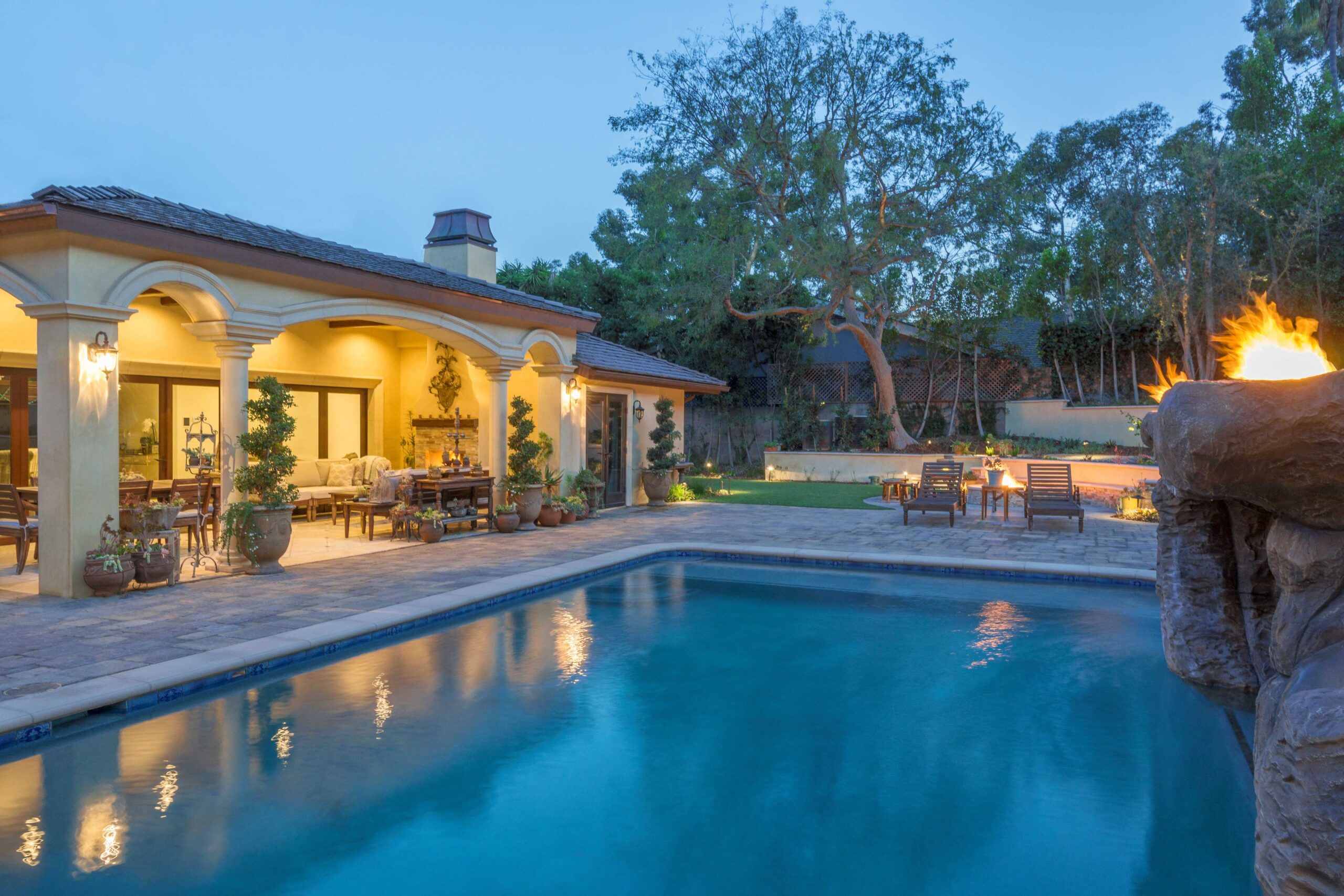 Classical white columns supporting a covered patio beside a backyard pool