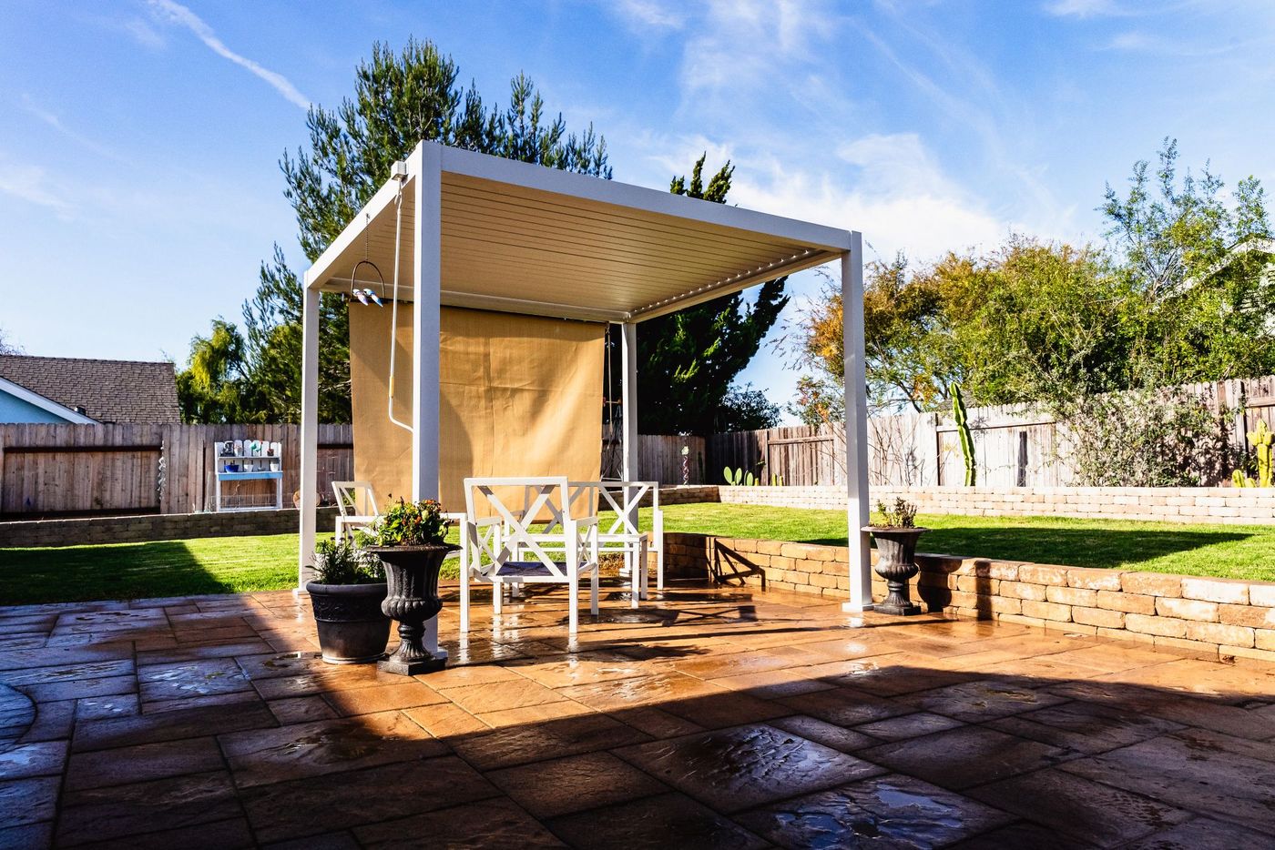 White pergola structure installed by a Santa Maria patio contractor over a custom paver patio with seating area.