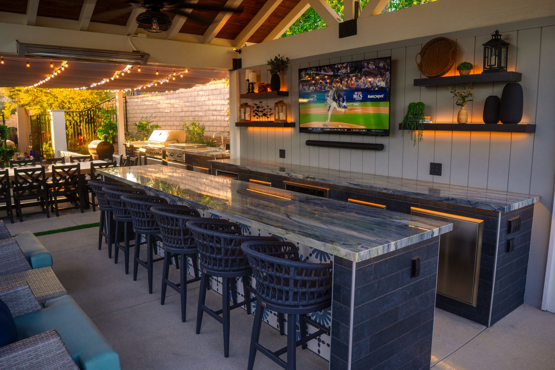Modern outdoor bar and entertainment space with shade structures, lounge seating, and bar counter
