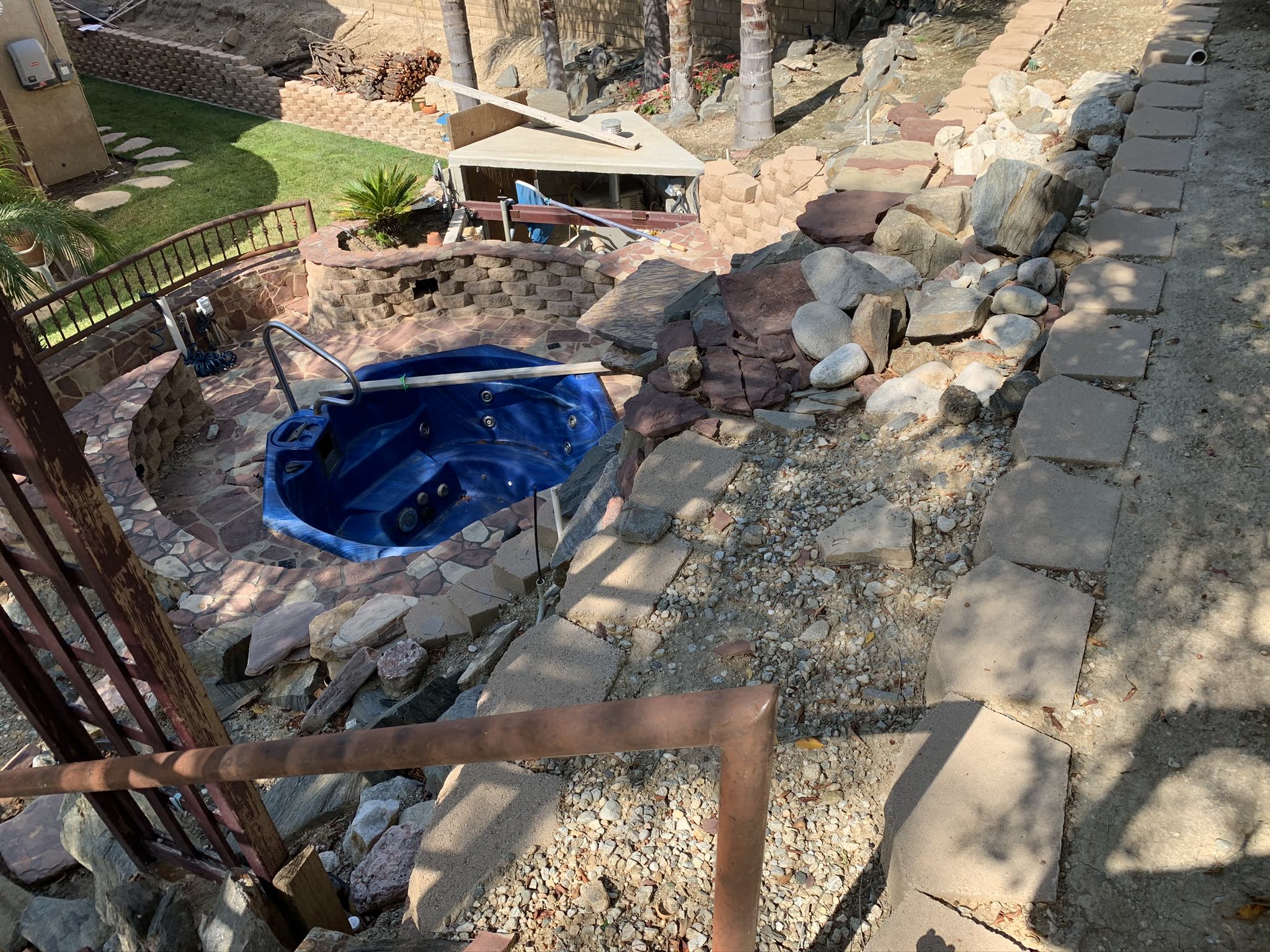 Blue spa surrounded by stone hardscape and landscape design