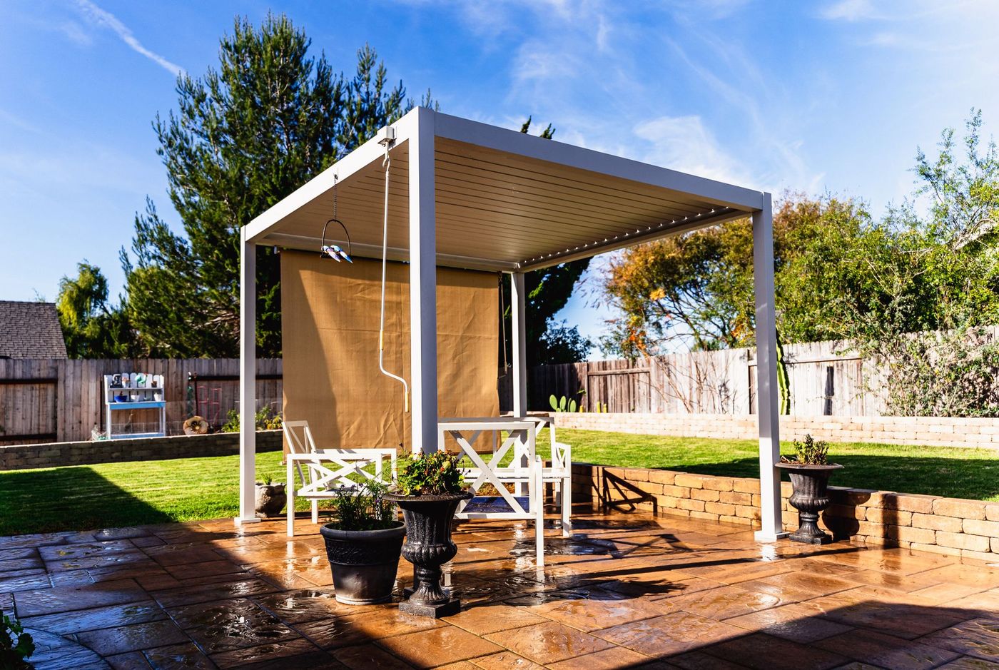 White pergola structure installed by a Santa Maria patio contractor over a custom paver patio with seating area.