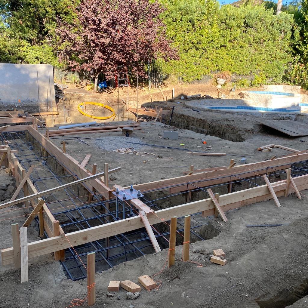 Hillside pool excavation with retaining wall forms and rebar under construction