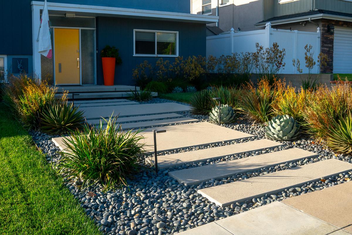 Front entry walkway of concrete pavers set in river rock with agaves, ornamental grasses, and path lighting