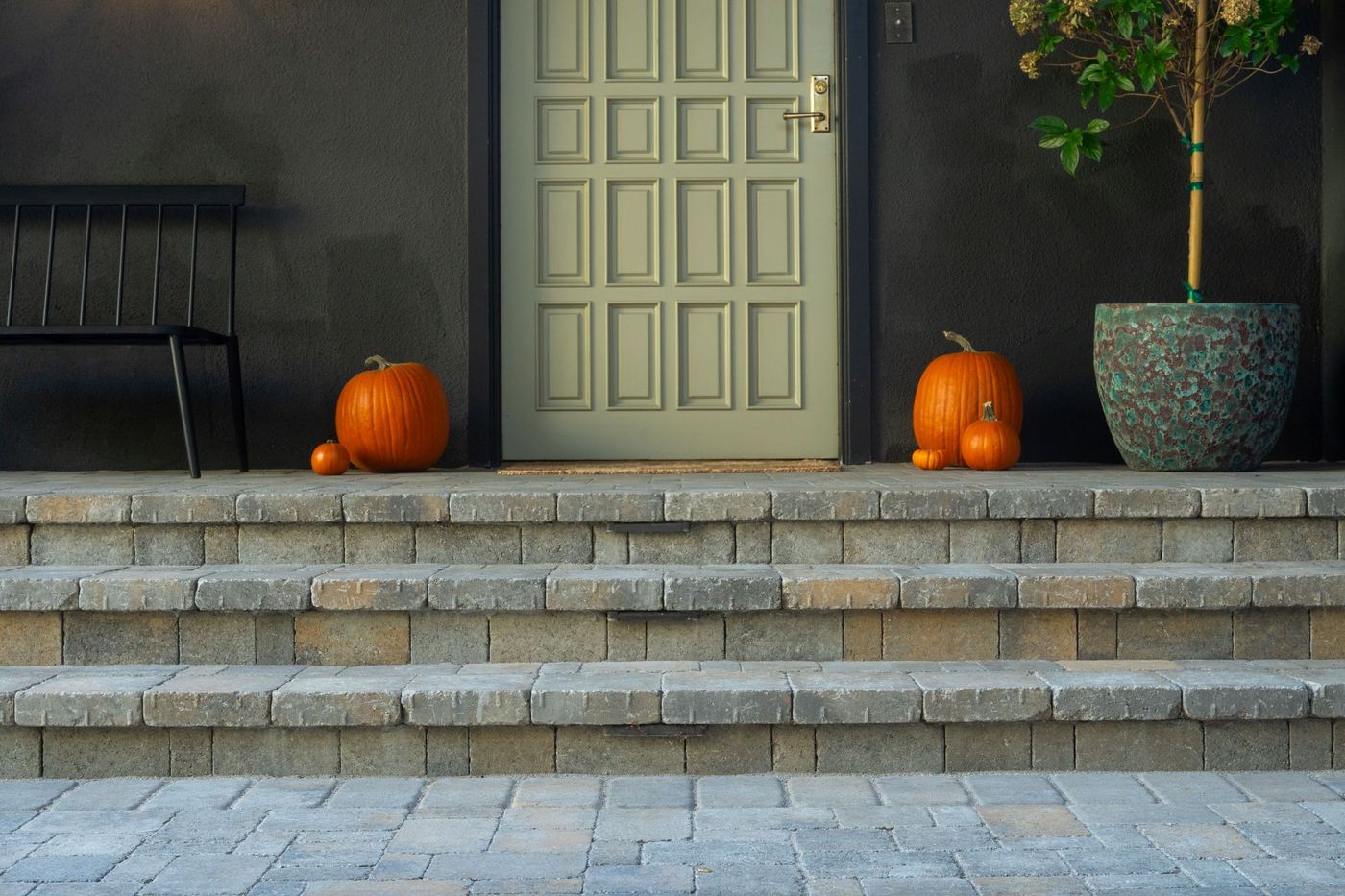 Close view of modern front entry door with stacked paver steps, decorative planters, and clean contemporary hardscape design