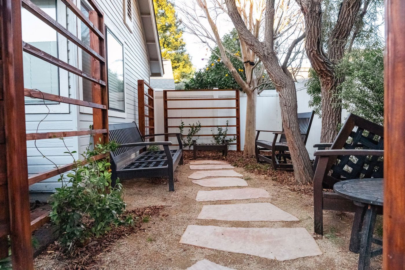 Cozy backyard seating area with gravel base and natural stone stepping path leading to benches.