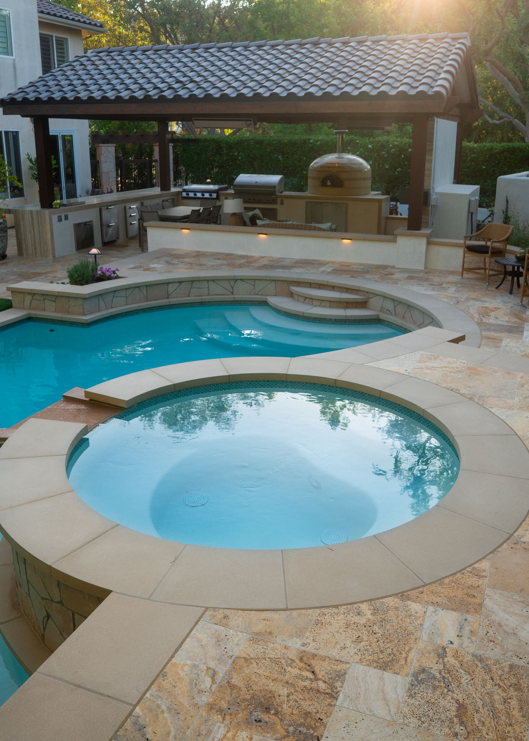 A natural stone spa raised above the pool, spilling into it over a stone lip