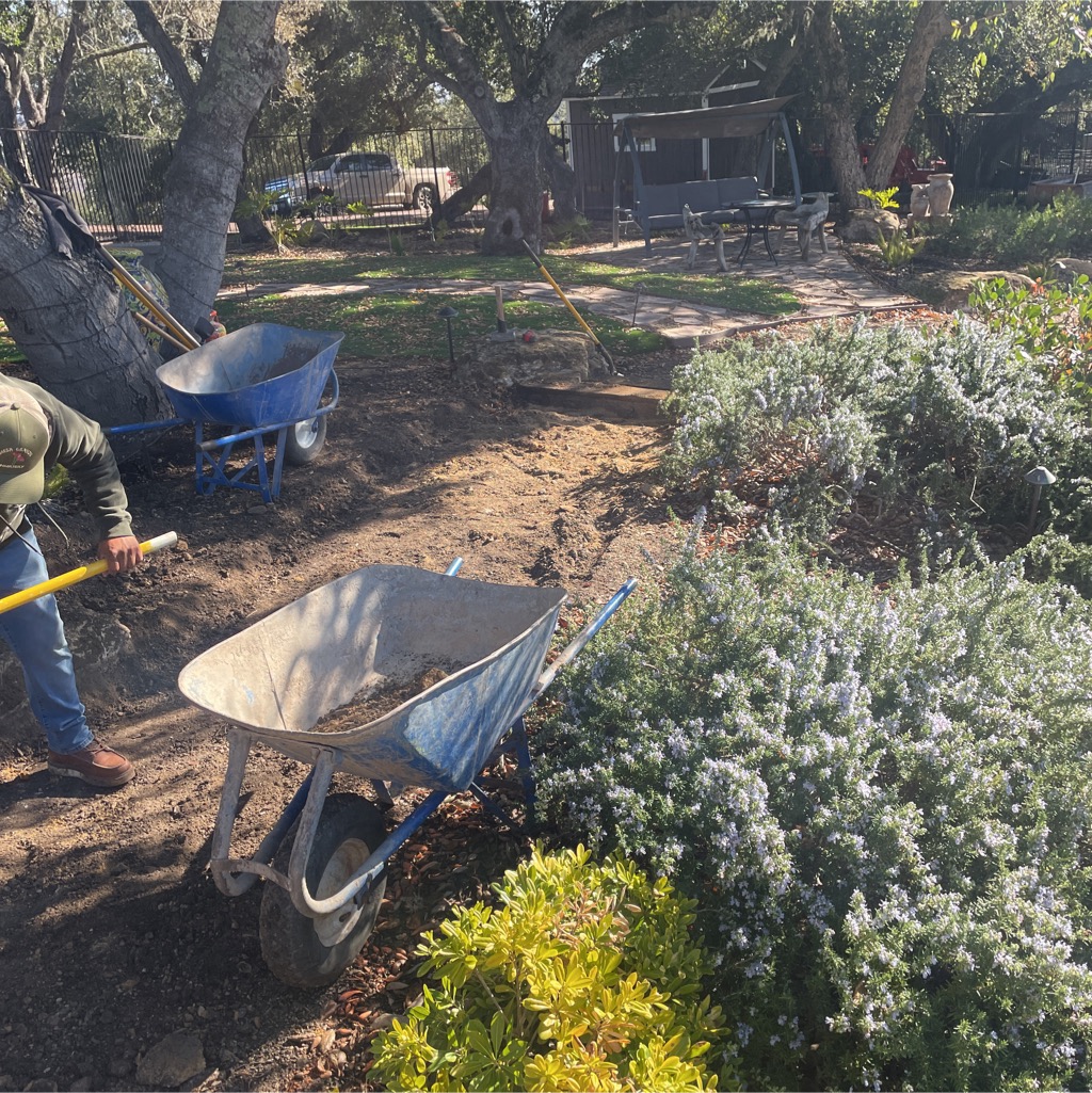 Workers moving materials by wheelbarrow during an in-progress Paso Robles-area landscape project