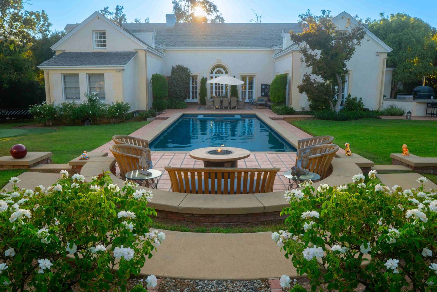 Luxury backyard swimming pool with fire pit seating and patio design by Pacific Outdoor Living