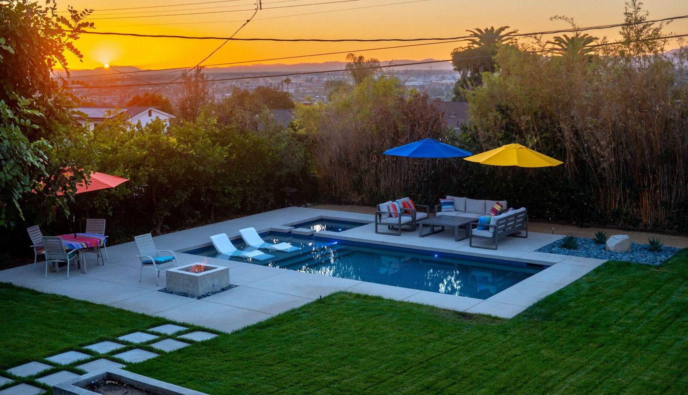A remodeled pool at sunset with new decking, lounge seating and a fire feature