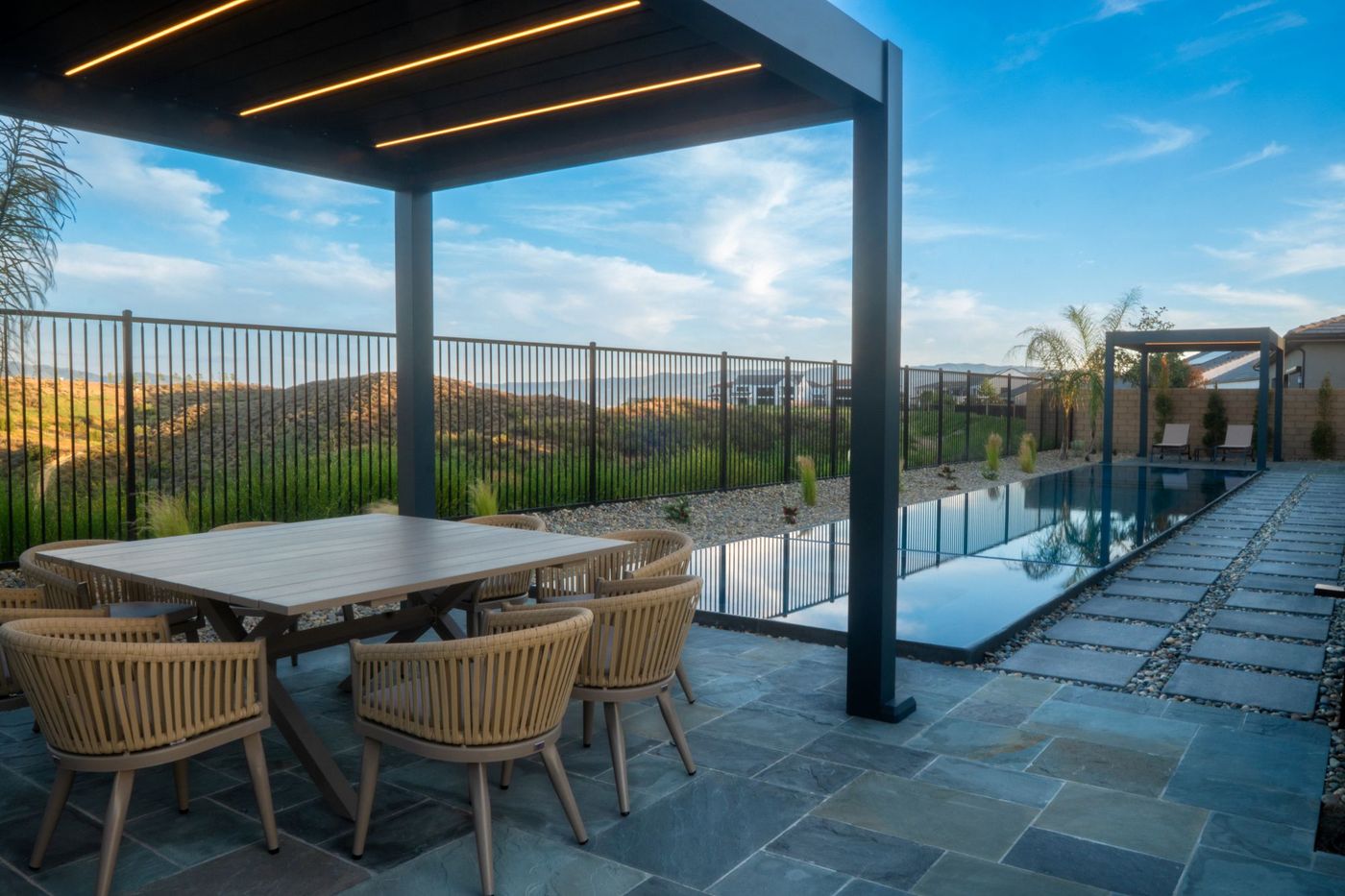 Modern pergola shading a lounge seating area in a hillside backyard