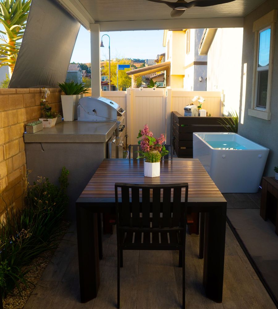 Efficient small-yard design combining outdoor dining table, built-in grill kitchen, privacy fencing, and modern plunge pool.