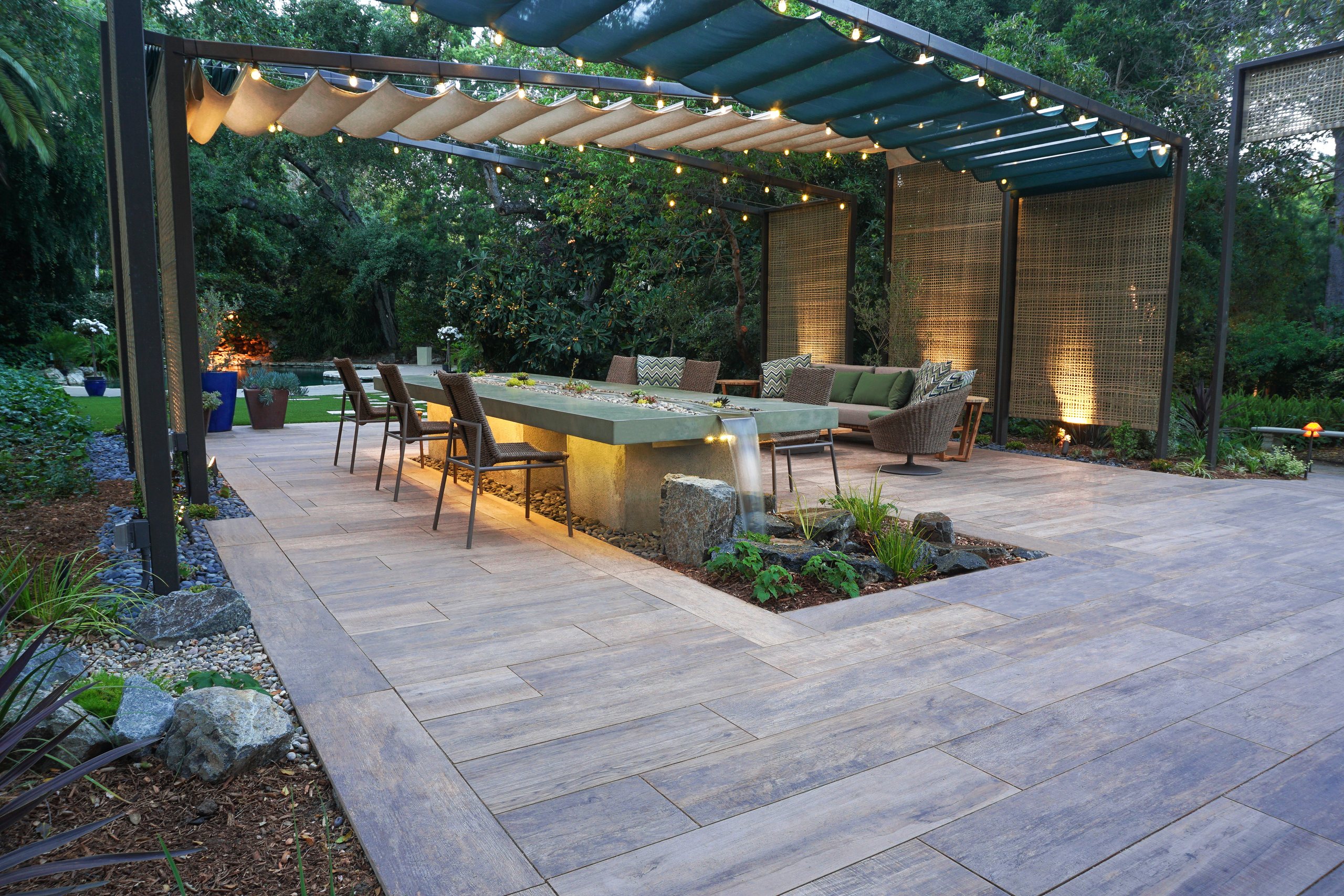 Pergola-covered dining area beside a formal garden water feature