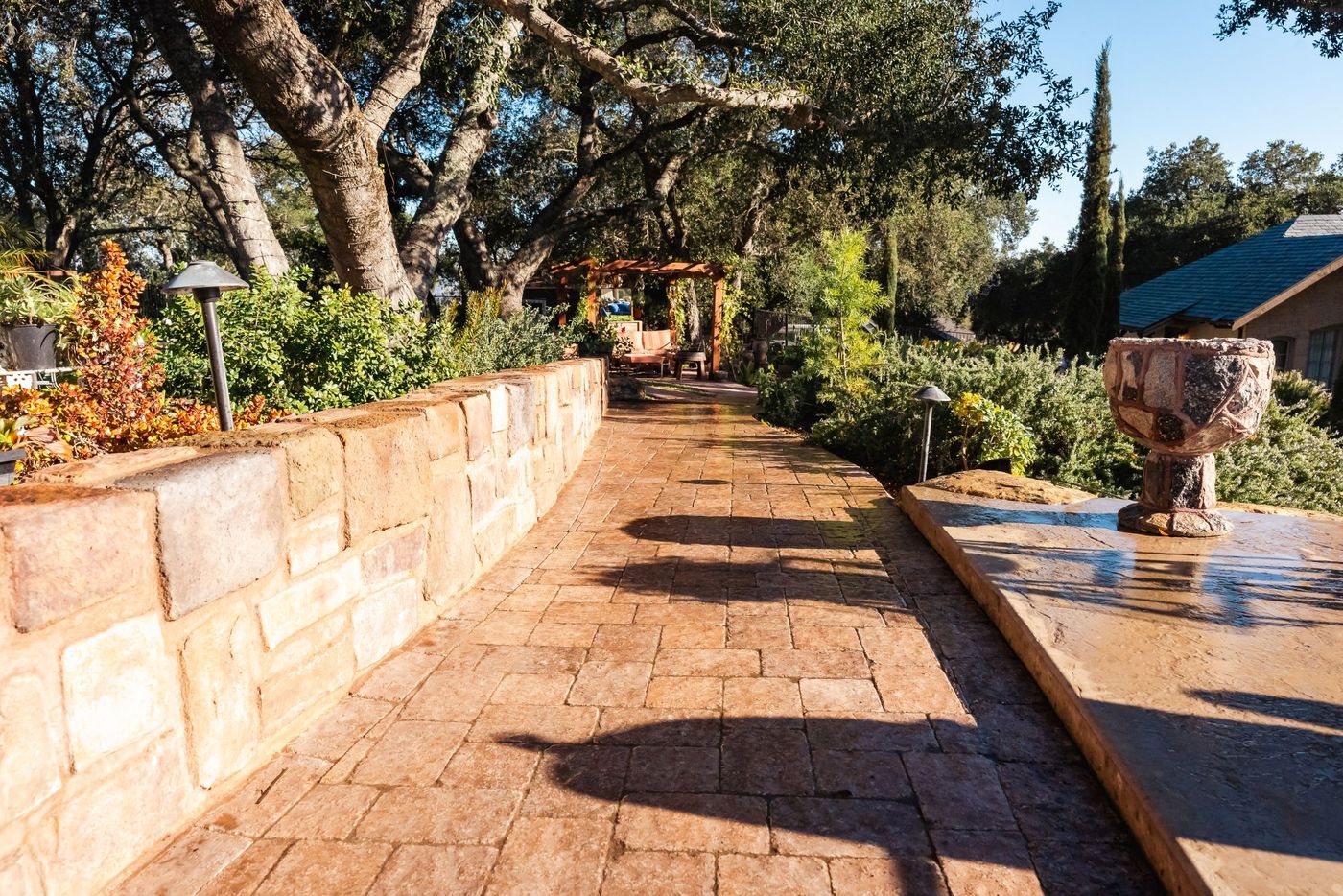 Curved garden pathway in Paso Robles featuring stamped concrete pavers and lush drought-tolerant landscaping.