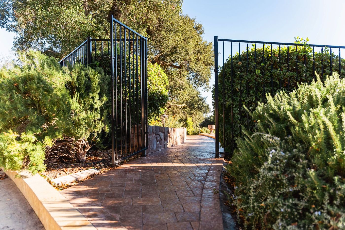 Decorative iron gate entrance opening to a stamped concrete paver walkway in Paso Robles, California.