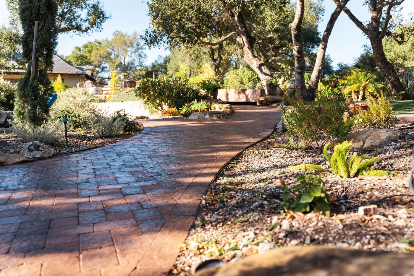 Low angle view of stone retaining wall alongside stamped concrete paver walkway in Paso Robles.