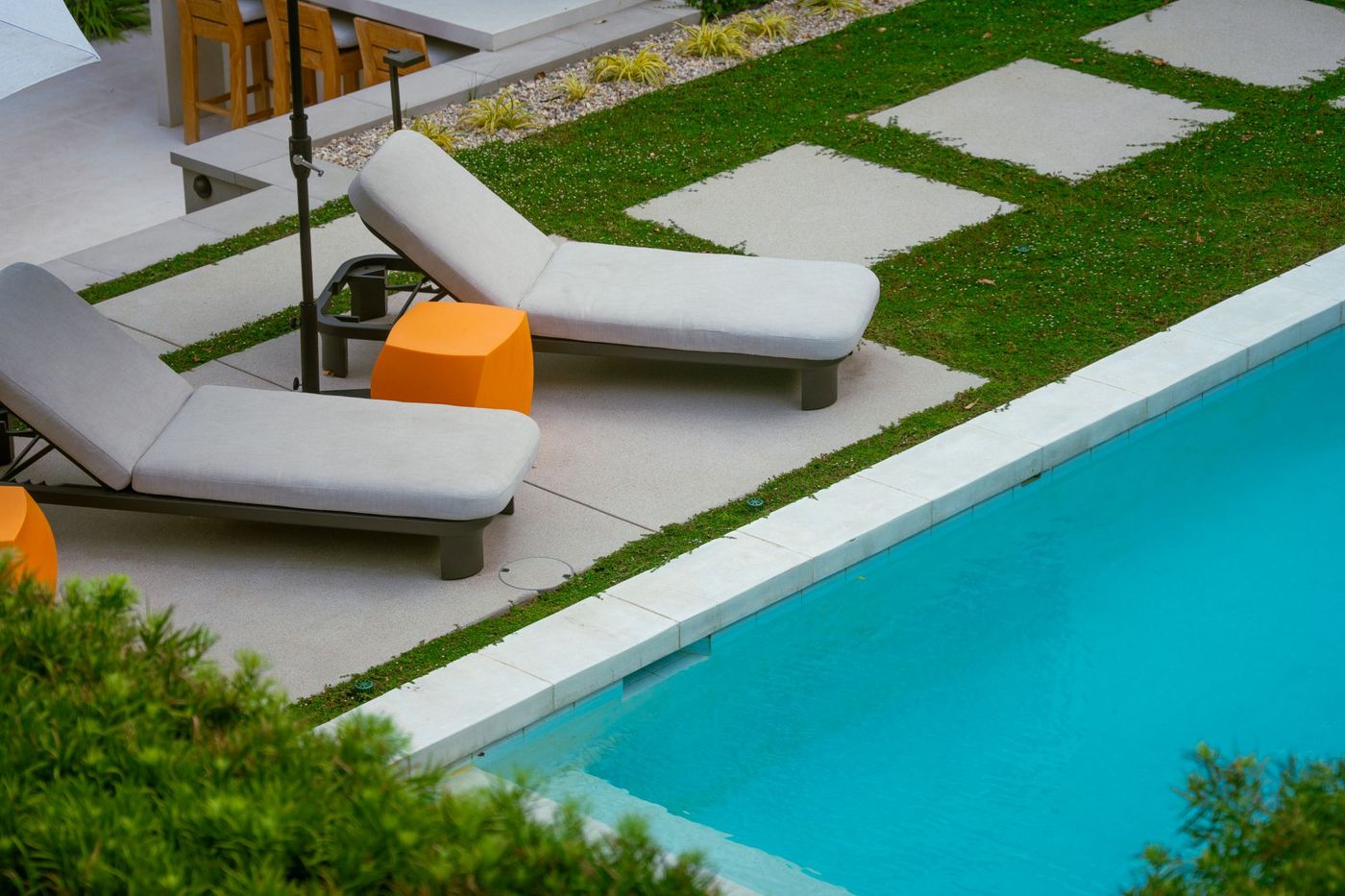Detailed view of cushioned lounge chair beside a modern swimming pool and clean concrete decking.