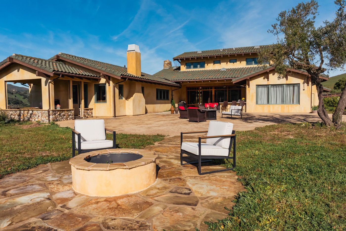 Stone patio fire pit installation in San Luis Obispo backyard with modern seating and hillside views.