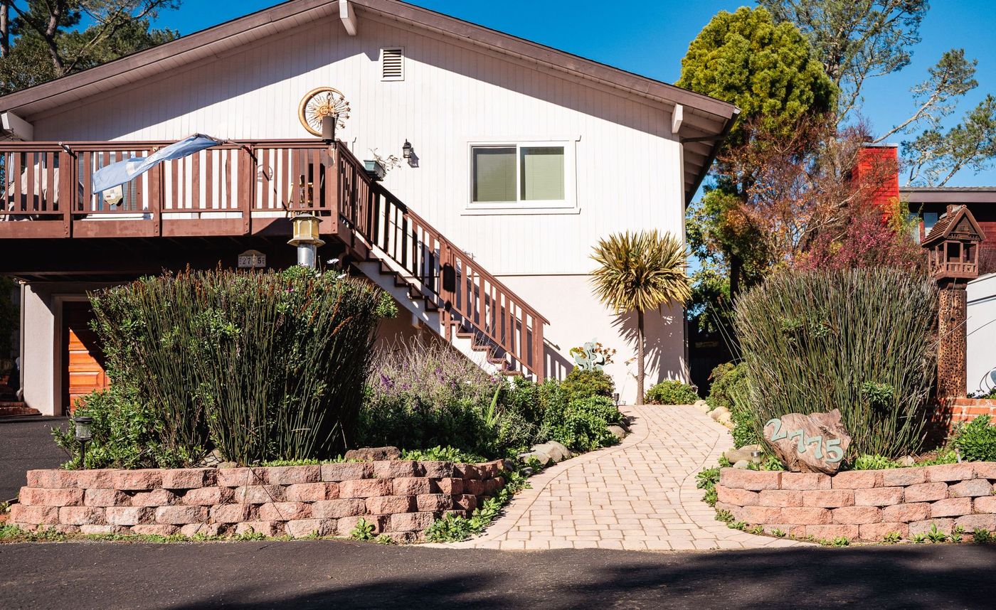 Front entry landscape in San Luis Obispo featuring a curved paver walkway, raised retaining walls, and lush planting beds.