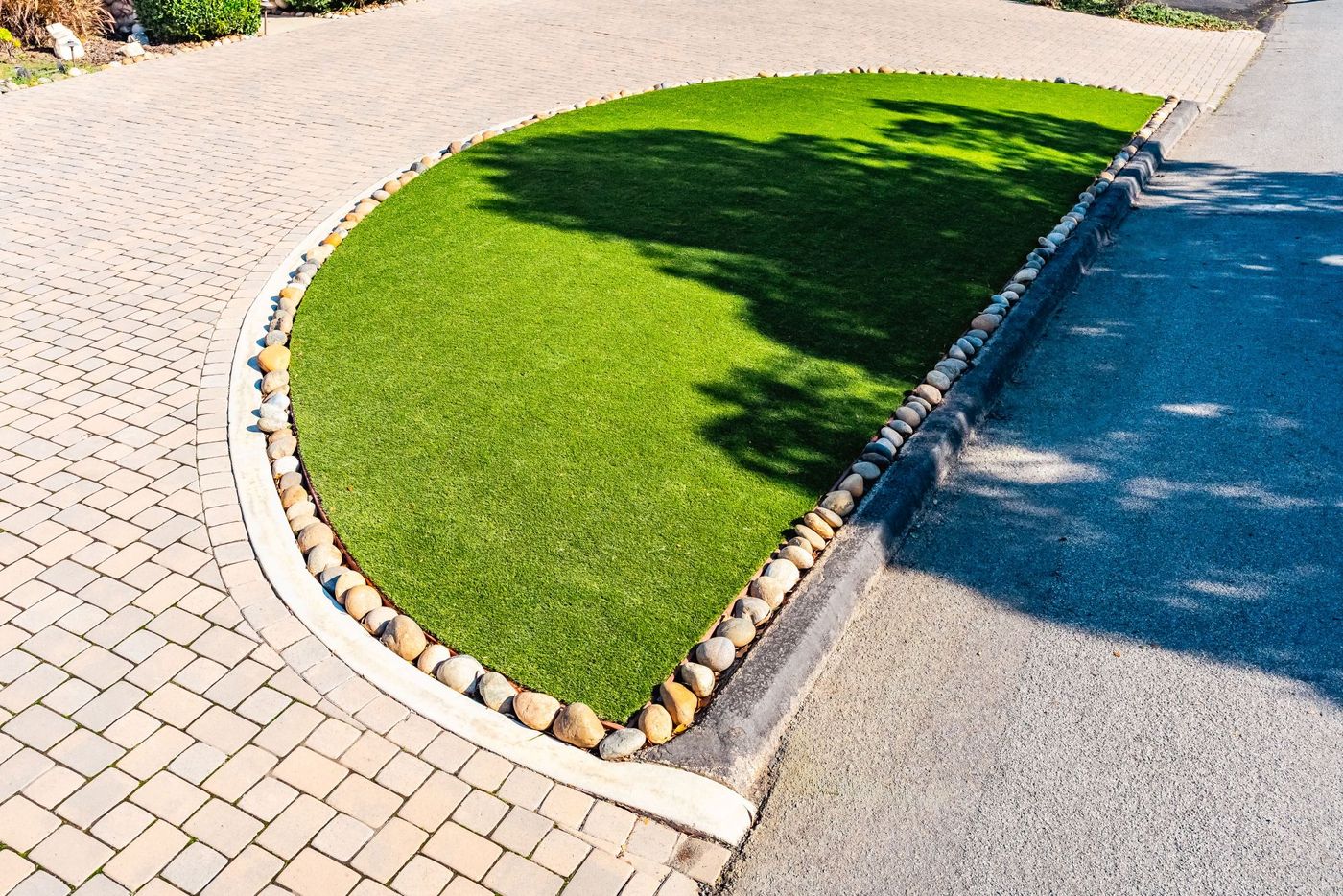 Water-efficient front yard landscape design in San Luis Obispo featuring artificial grass, curved concrete edging, and paver hardscape.