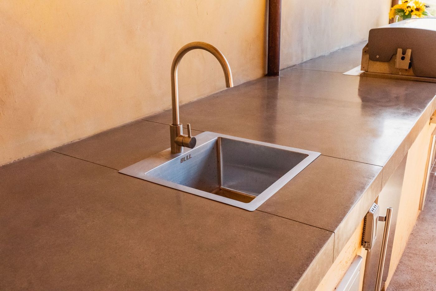 Close-up of outdoor kitchen sink and concrete countertop in a San Luis Obispo backyard entertainment space.